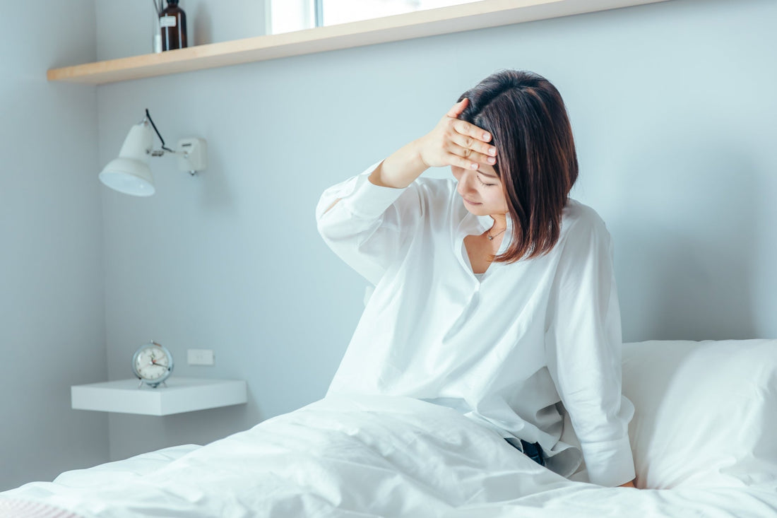 二日酔いでベッドの上で辛そうにしている女性